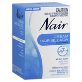 Nair hair bleach cream for face and body in a blue box with baby oil and vitamin E, dermatologically tested.