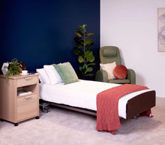 Bock® v2 adjustable height 4-section single electric bed in a cozy room setting with a nightstand and greenery.